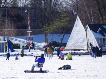 An ice boat and a snowkiter share the field at teh Reeds Lake Ice Fly