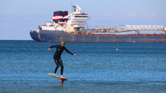 Click to go to the hydrofoil blog A rider pumps his hydrofoil with a freighter in the background